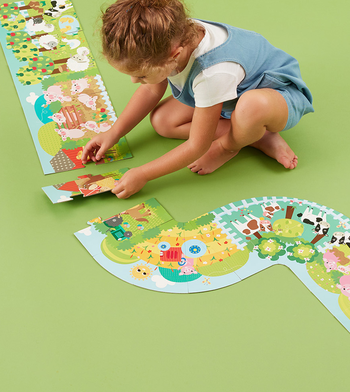 Niña montando un puzzle educativo de animales de Apli Kids sobre fondo verde, diseño por Nomon Design, agencia de branding