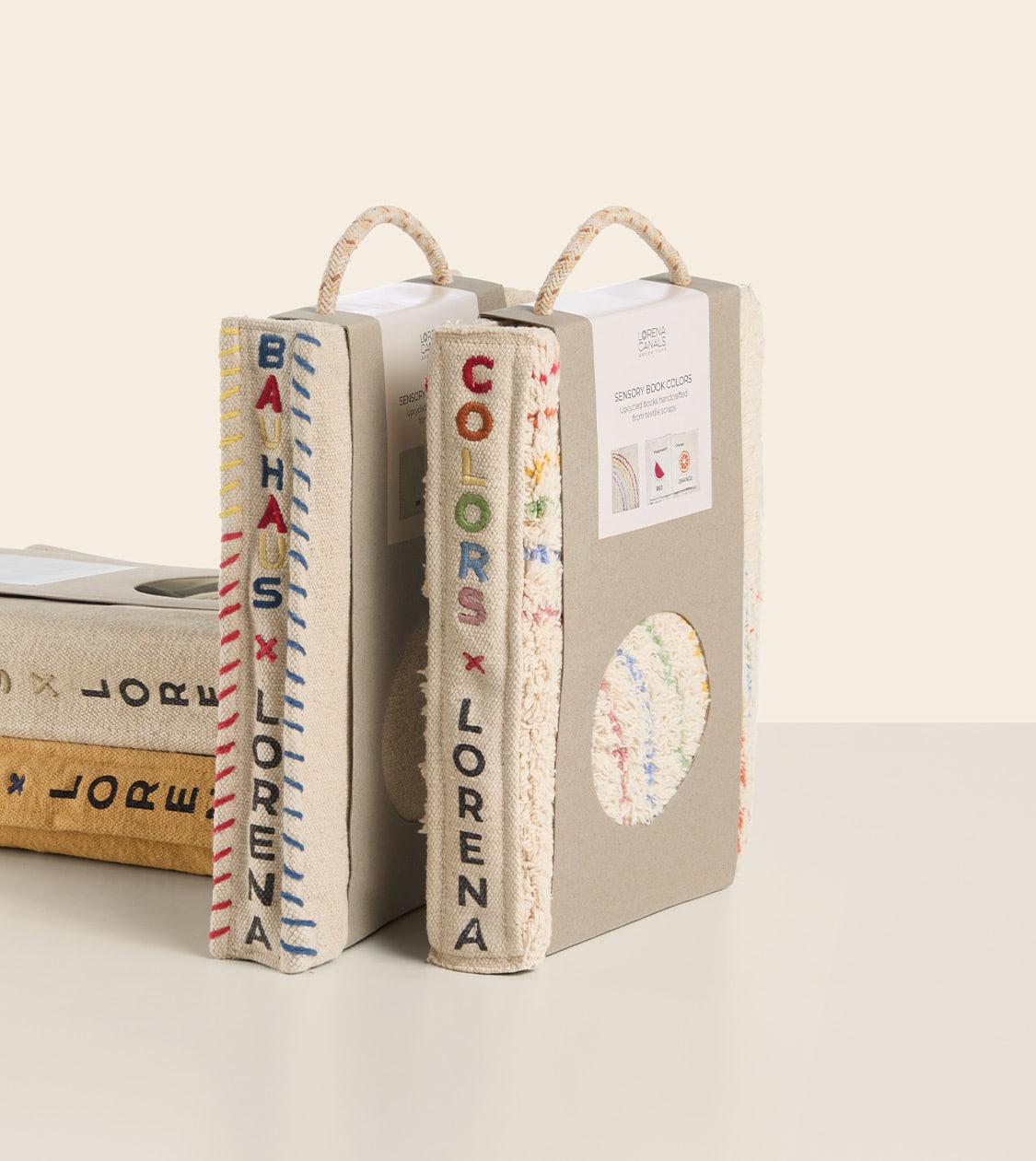 Diseño de packaging para libros sensoriales de Lorena Canals en formato textil, con lomos bordados y asas de cordón, por Nomon Design agencia de branding